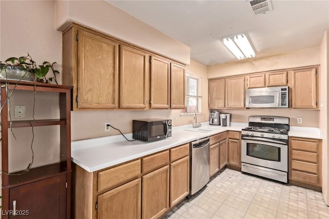 kitchen with light floors, stainless steel appliances, light countertops, visible vents, and a sink