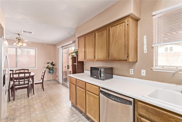 kitchen featuring ceiling fan, stainless steel appliances, a sink, light countertops, and light floors