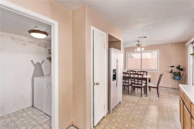 interior space featuring stainless steel refrigerator with ice dispenser, light floors, washing machine and clothes dryer, light countertops, and a ceiling fan