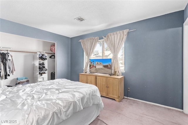 bedroom with a textured ceiling, light colored carpet, visible vents, baseboards, and a closet