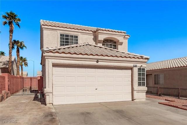 mediterranean / spanish home featuring a tile roof, driveway, fence, and stucco siding