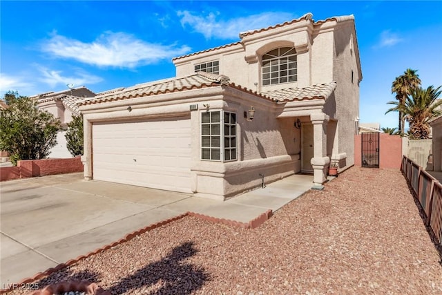 mediterranean / spanish house featuring a tile roof, stucco siding, a gate, a garage, and driveway