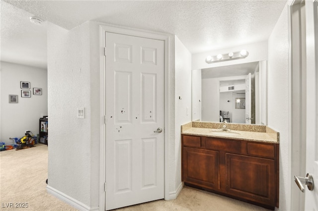 bathroom with a textured ceiling, a textured wall, vanity, and baseboards