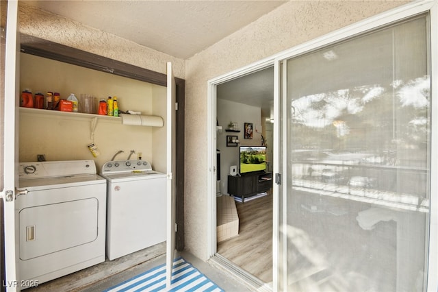 clothes washing area with washing machine and dryer and light wood-style flooring