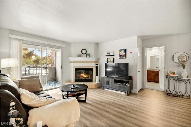 living room featuring light wood-style flooring and a tiled fireplace