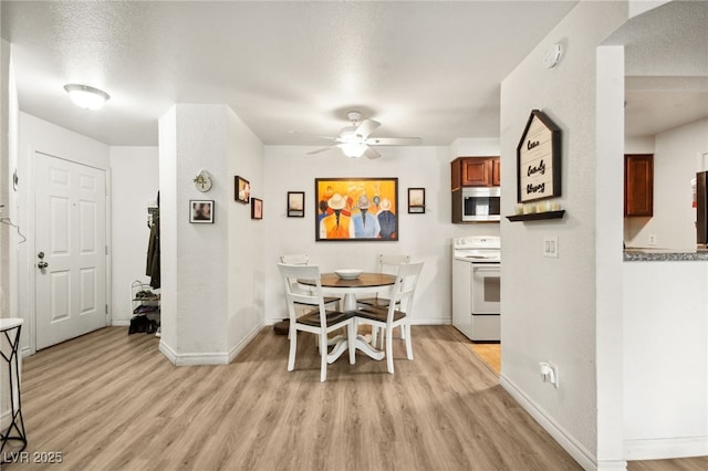 dining room with light wood finished floors, a ceiling fan, and baseboards