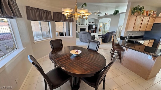 dining room with light tile patterned floors, baseboards, arched walkways, an inviting chandelier, and a fireplace