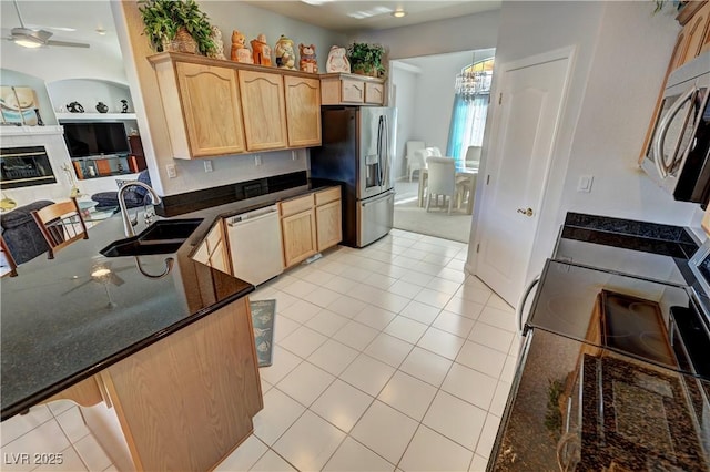 kitchen with appliances with stainless steel finishes, light brown cabinetry, built in shelves, a sink, and ceiling fan with notable chandelier