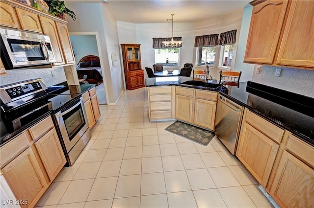 kitchen featuring light tile patterned floors, light brown cabinetry, appliances with stainless steel finishes, a sink, and a peninsula