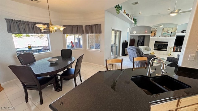 kitchen featuring built in features, decorative light fixtures, a fireplace, visible vents, and a sink