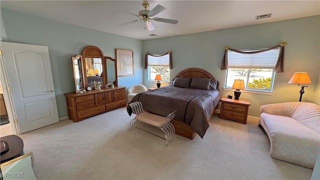 carpeted bedroom featuring ceiling fan, multiple windows, visible vents, and baseboards