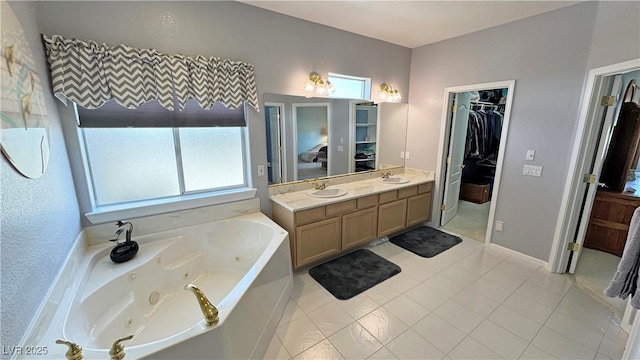 full bathroom with double vanity, a jetted tub, a sink, and a walk in closet