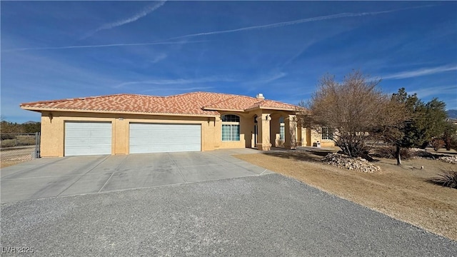 mediterranean / spanish-style house featuring a garage, driveway, a tiled roof, and stucco siding