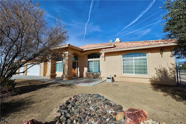 back of house with a garage, a tile roof, and stucco siding