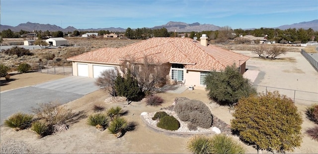 view of front facade featuring a garage, concrete driveway, a mountain view, and fence