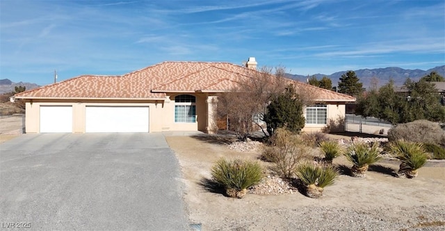 view of front facade featuring a garage, a mountain view, driveway, and stucco siding