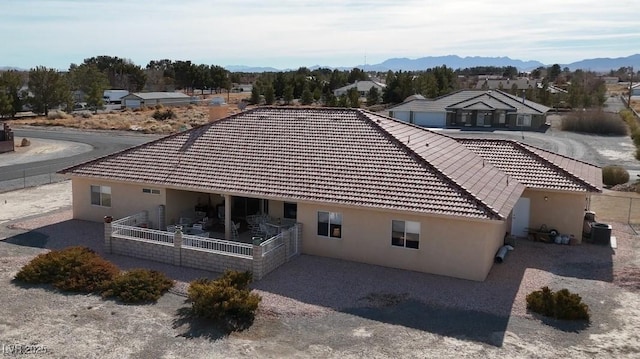 rear view of house featuring a tiled roof, central AC unit, a mountain view, and stucco siding