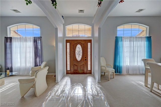 foyer entrance featuring a towering ceiling, visible vents, arched walkways, and carpet flooring