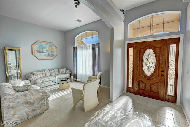 tiled entrance foyer featuring carpet floors, visible vents, and baseboards