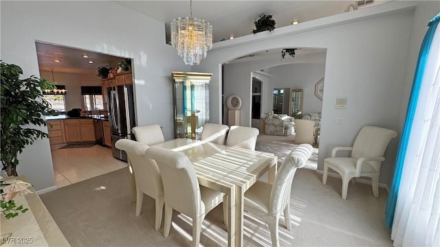 dining area with an inviting chandelier, light tile patterned floors, arched walkways, and light colored carpet