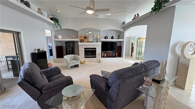 living area featuring ceiling fan, built in shelves, light tile patterned floors, and a tile fireplace