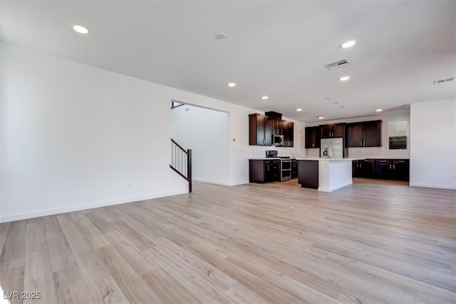 unfurnished living room featuring recessed lighting, visible vents, light wood-type flooring, baseboards, and stairs