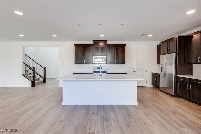 kitchen featuring stainless steel appliances, light countertops, light wood-style flooring, and decorative backsplash