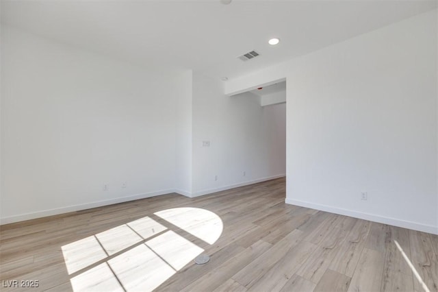 spare room featuring light wood finished floors, baseboards, visible vents, and recessed lighting