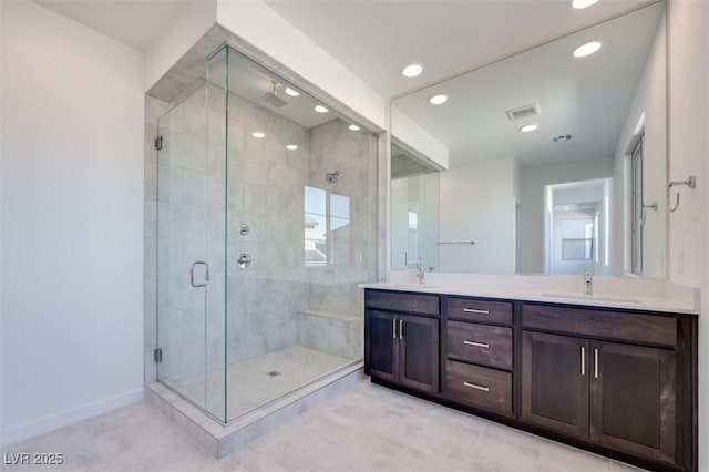 bathroom featuring double vanity, a shower stall, baseboards, and a sink