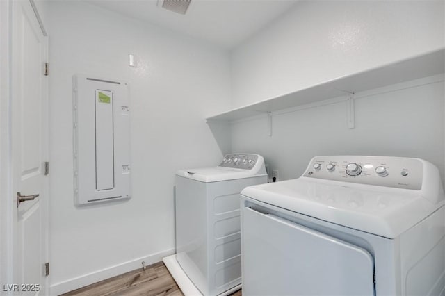 laundry room with laundry area, light wood finished floors, electric panel, baseboards, and separate washer and dryer