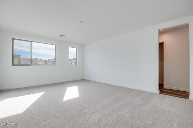 empty room featuring carpet, visible vents, and baseboards