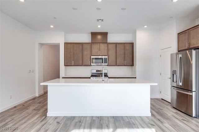 kitchen with light countertops, appliances with stainless steel finishes, an island with sink, and recessed lighting