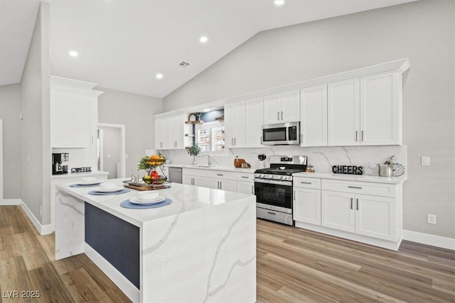 kitchen featuring light wood-style flooring, appliances with stainless steel finishes, white cabinets, and a center island