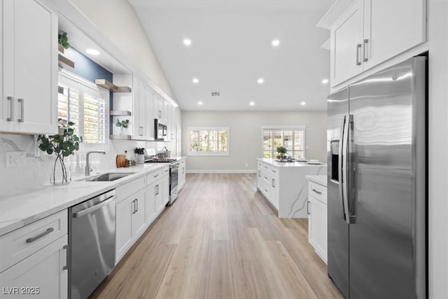 kitchen featuring open shelves, stainless steel appliances, lofted ceiling, decorative backsplash, and a sink