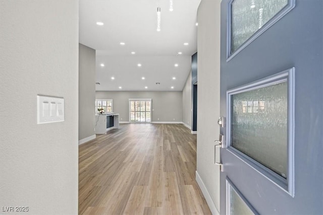 living area with light wood-style floors, recessed lighting, a towering ceiling, and baseboards