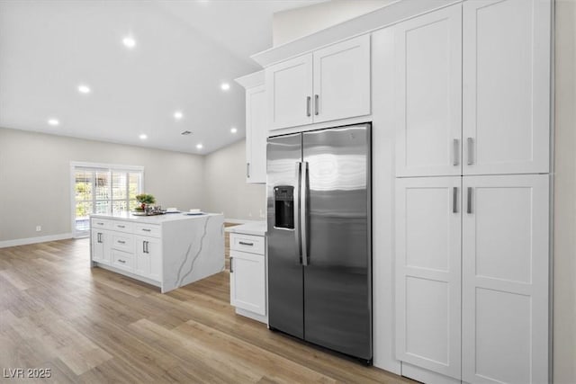 kitchen with light wood finished floors, stainless steel fridge, white cabinetry, and recessed lighting