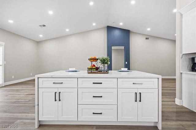 kitchen featuring light stone counters, light wood-style floors, visible vents, and white cabinetry