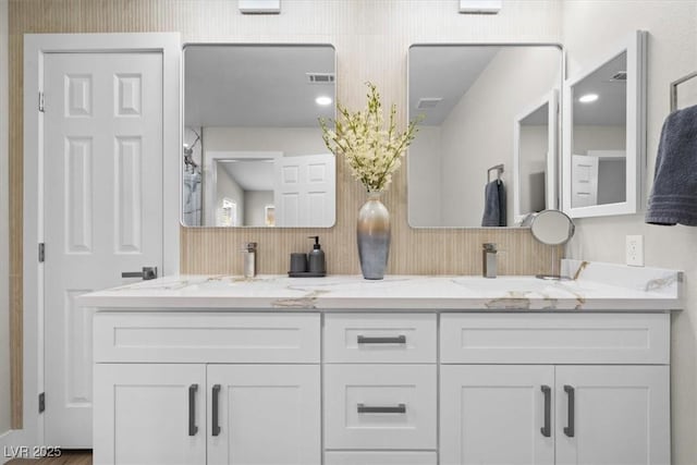 bathroom with double vanity, a sink, and visible vents