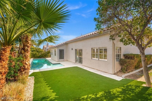 rear view of house featuring a yard, a patio, an outdoor pool, and stucco siding