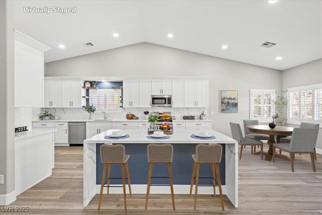 kitchen featuring white cabinetry, a kitchen bar, visible vents, and stainless steel appliances