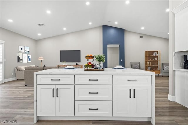 kitchen featuring white cabinets, light wood-style floors, visible vents, and open floor plan