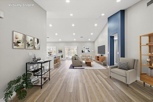 living area with high vaulted ceiling, light wood-type flooring, visible vents, and recessed lighting