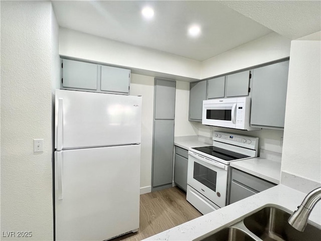 kitchen with white appliances, light countertops, light wood-style flooring, and gray cabinetry