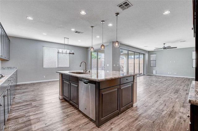 kitchen with light wood finished floors, stainless steel dishwasher, a sink, and visible vents