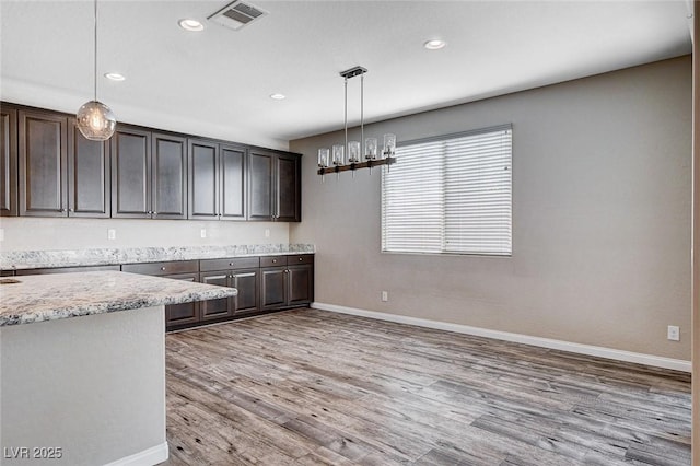 kitchen with light wood-style flooring, a notable chandelier, visible vents, baseboards, and dark brown cabinets