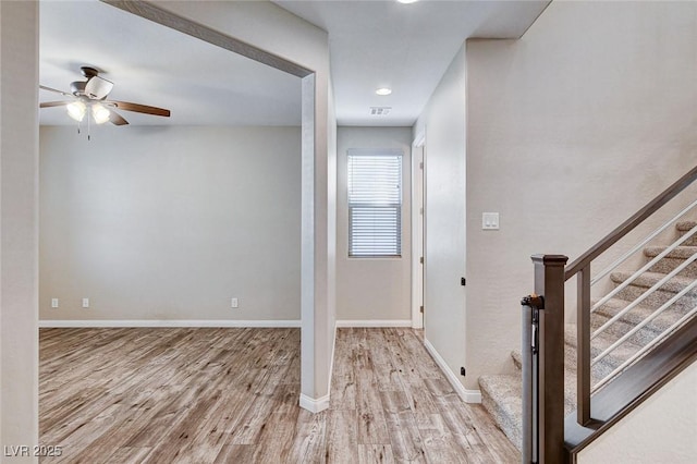 interior space featuring ceiling fan, stairway, baseboards, and wood finished floors