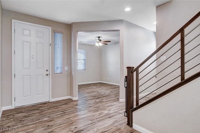 entryway with stairway, wood finished floors, a ceiling fan, and baseboards