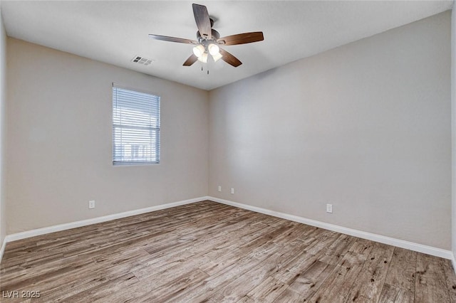 spare room with a ceiling fan, baseboards, visible vents, and wood finished floors