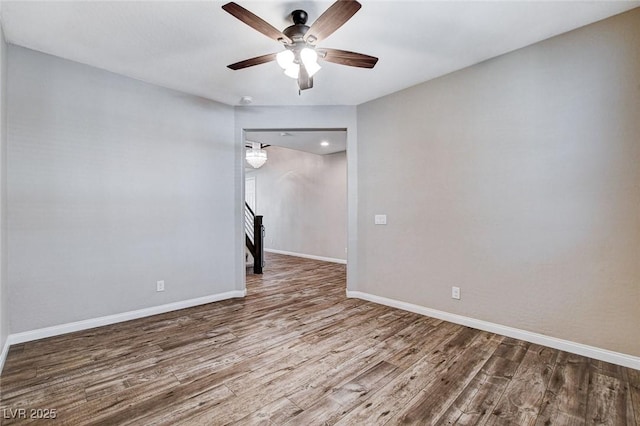 spare room with a ceiling fan, stairs, baseboards, and wood finished floors