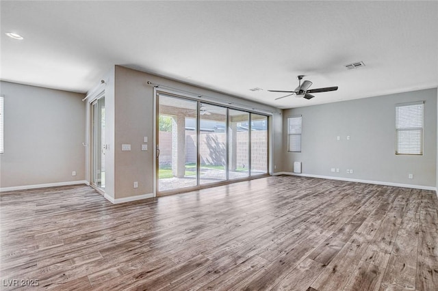 unfurnished living room with wood finished floors, visible vents, and baseboards